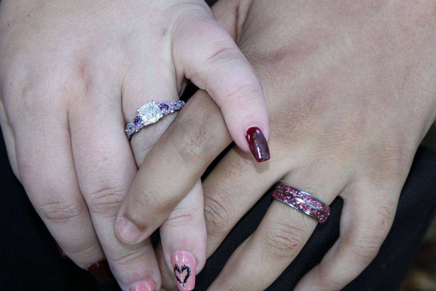 Close-up of couple holding hands with engagement rings, romantic detail shot