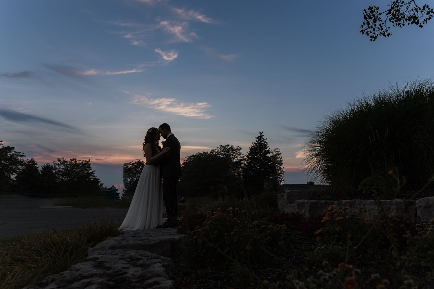 Bride and groom resting their foreheads together in front of a dark colourful sunset for a calm wedding photo moment in hamilton, ontario.