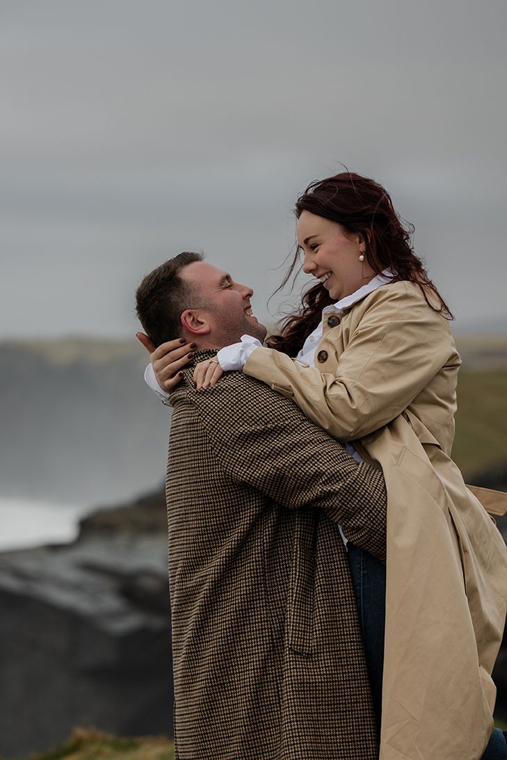 Adventure-loving couple celebrating love during cinematic stormy sunset portraits at Cliffs of Moher