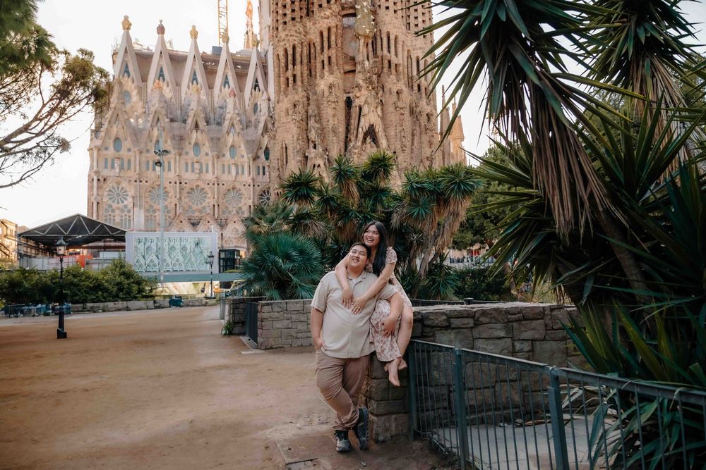 Wide shot of the couple framed by the trees and the basilica towers.