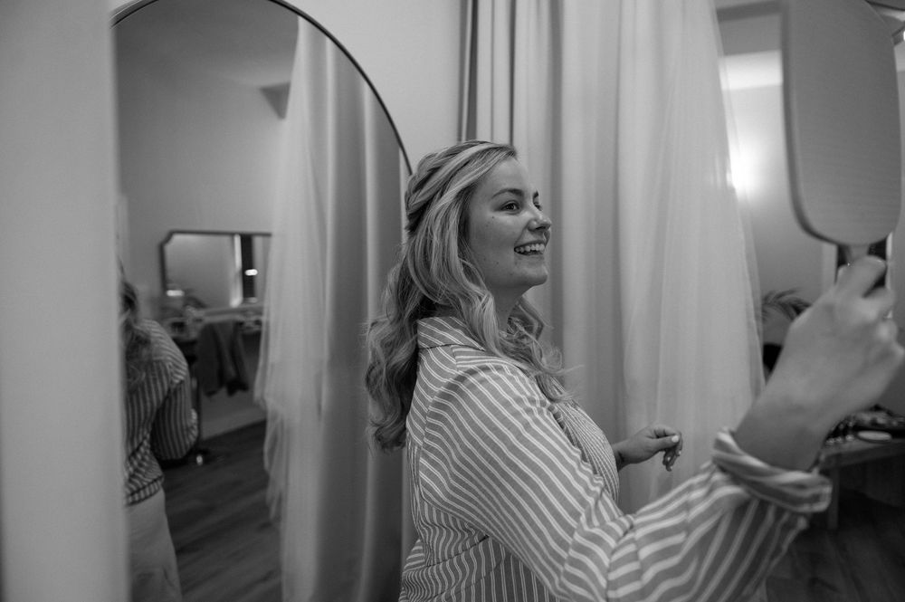 Person laughing while getting ready in dressing room with mirrors.