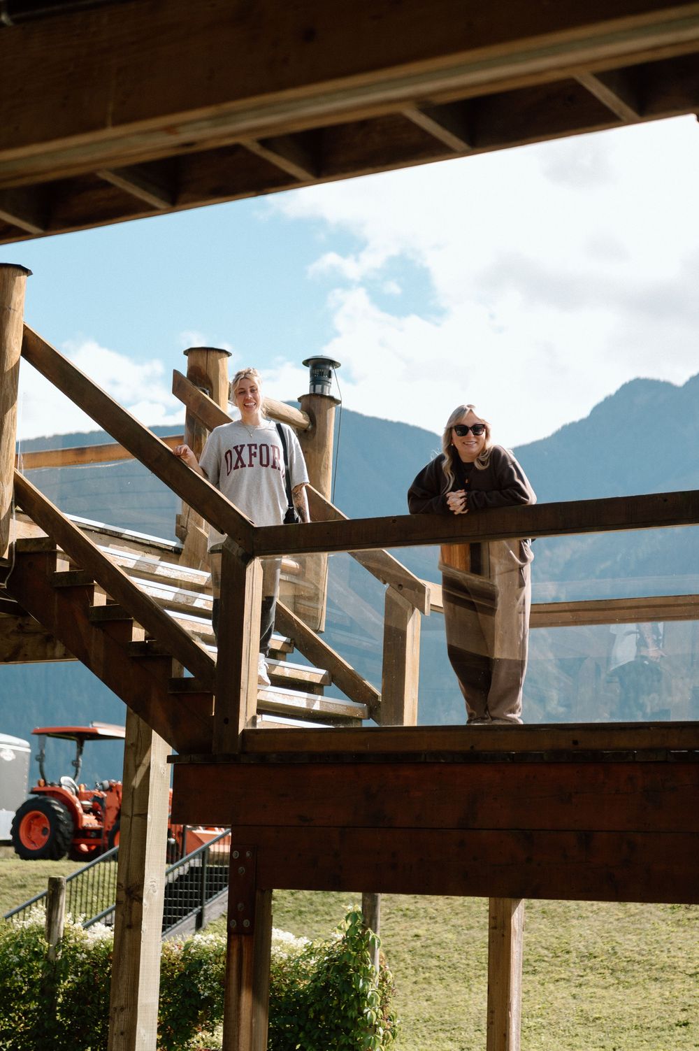 Wooden deck platform overlooking mountain scenery with people enjoying the view.
