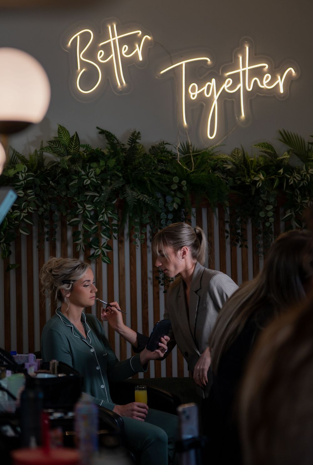 Illuminated neon sign creates warm ambiance against wooden wall with tropical greenery decor.