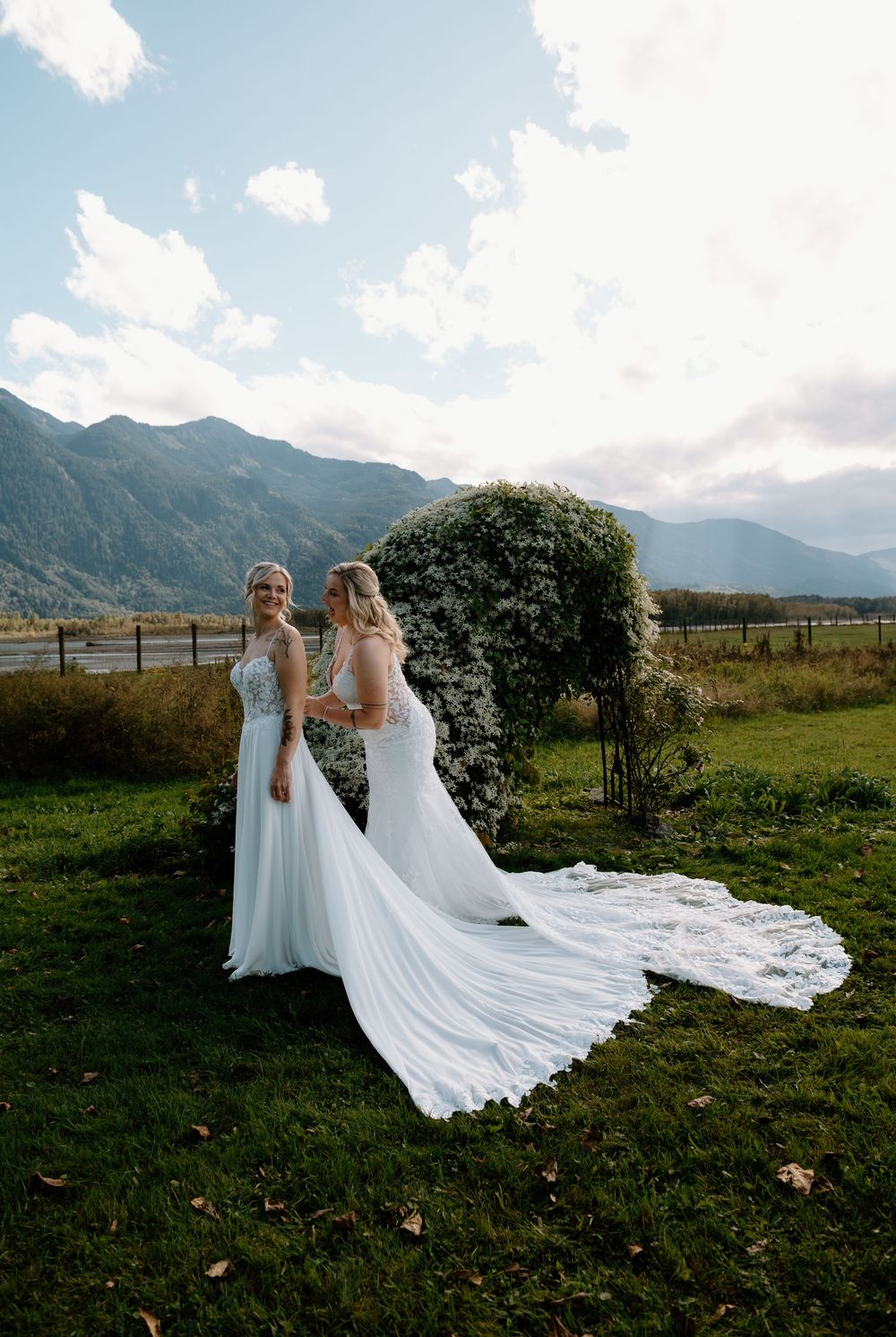 Wedding dresses flowing in the wind against mountain landscape on sunny day.