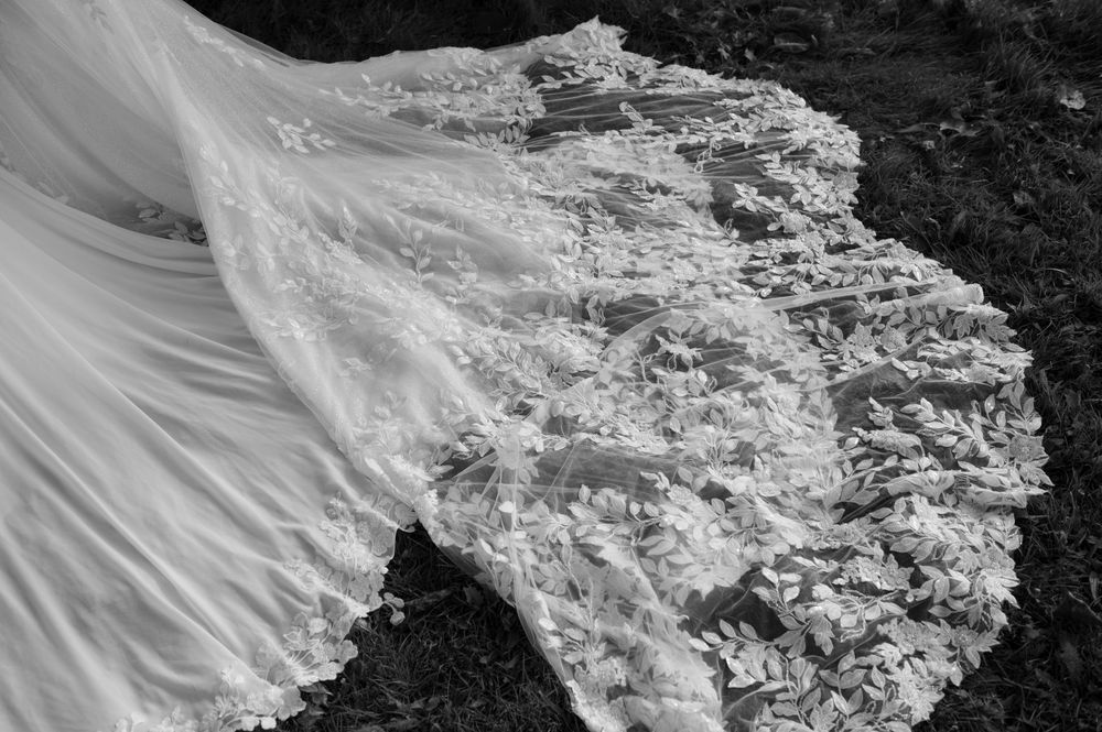 Close-up details of intricate white lace wedding dress fabric with delicate floral patterns.