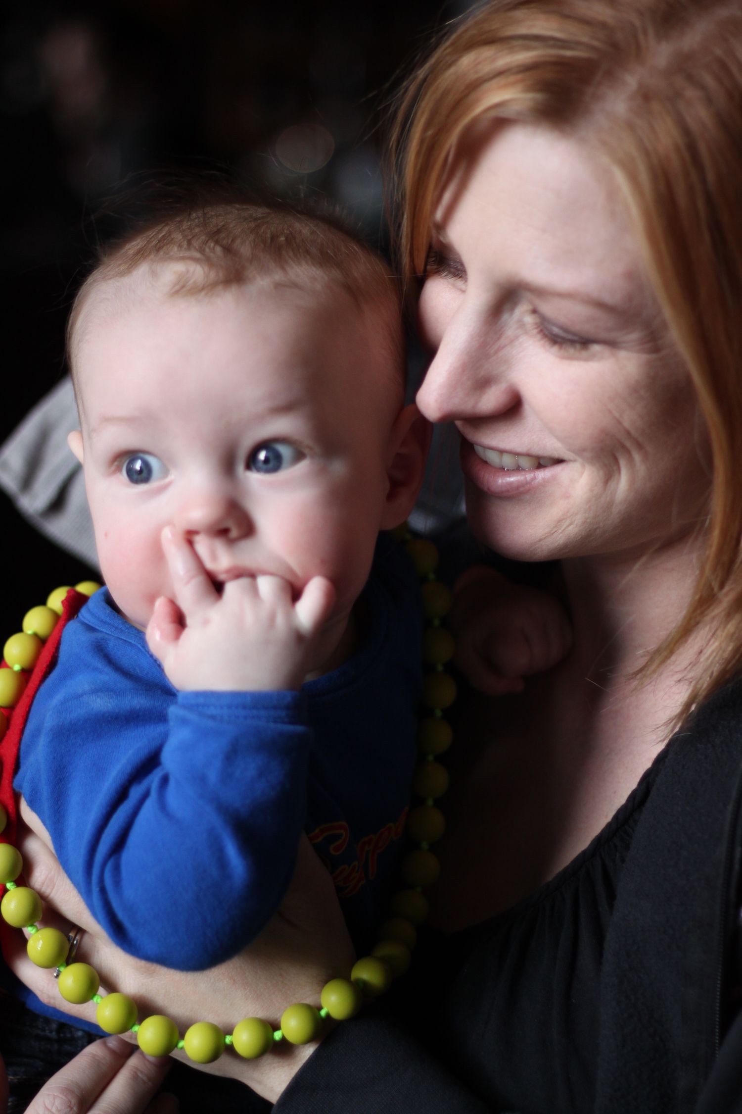 A series of tender moments between parent and child wearing a bright yellow necklace and blue shirt.