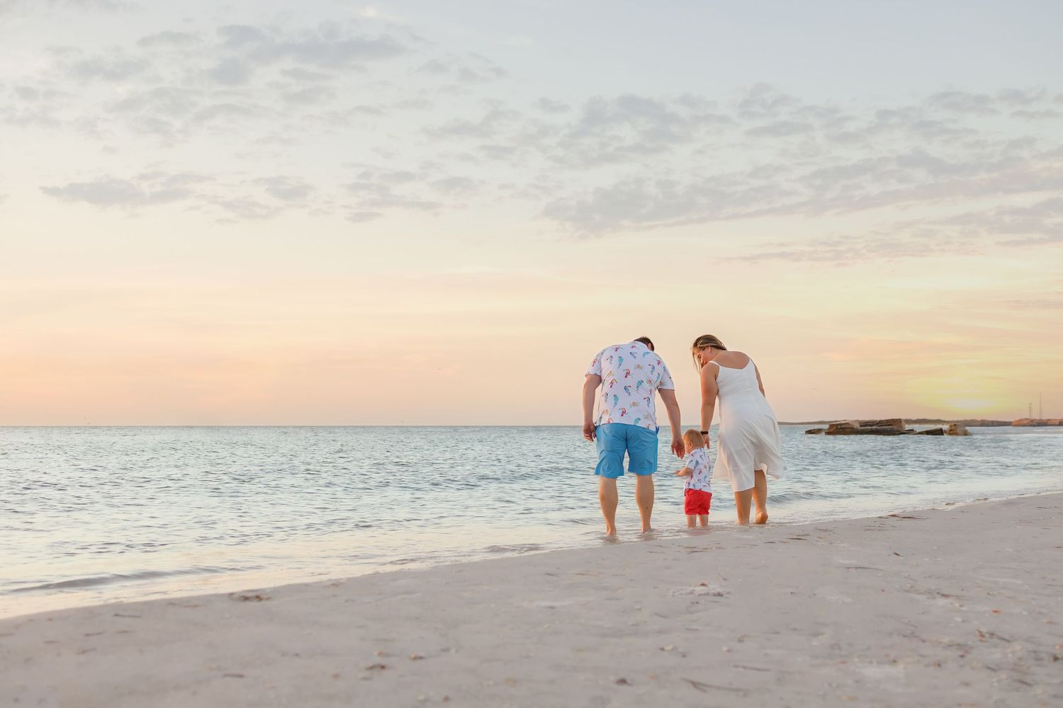 Family walking along pristine beach during golden hour photo session.