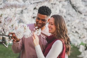 Couple admiring cherry blossoms in springtime while sharing a tender moment.