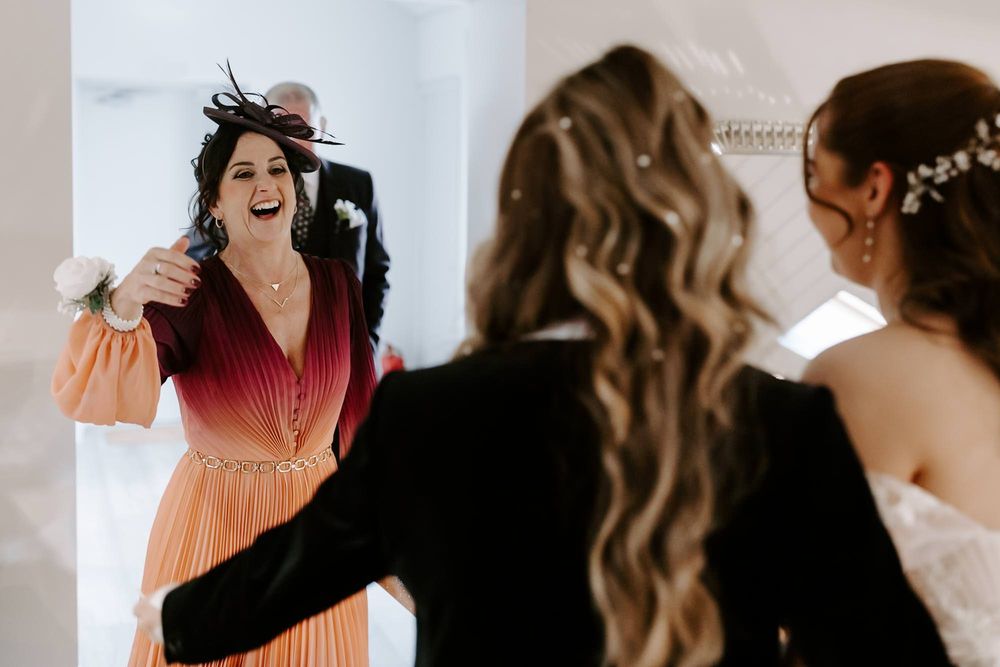 Joyful moment captured during wedding preparations showing laughter and celebration in a bright indoor setting.
