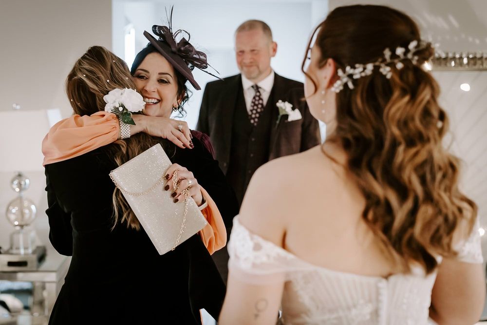 Candid wedding moment captured in black and white showing joyful reactions during preparation.