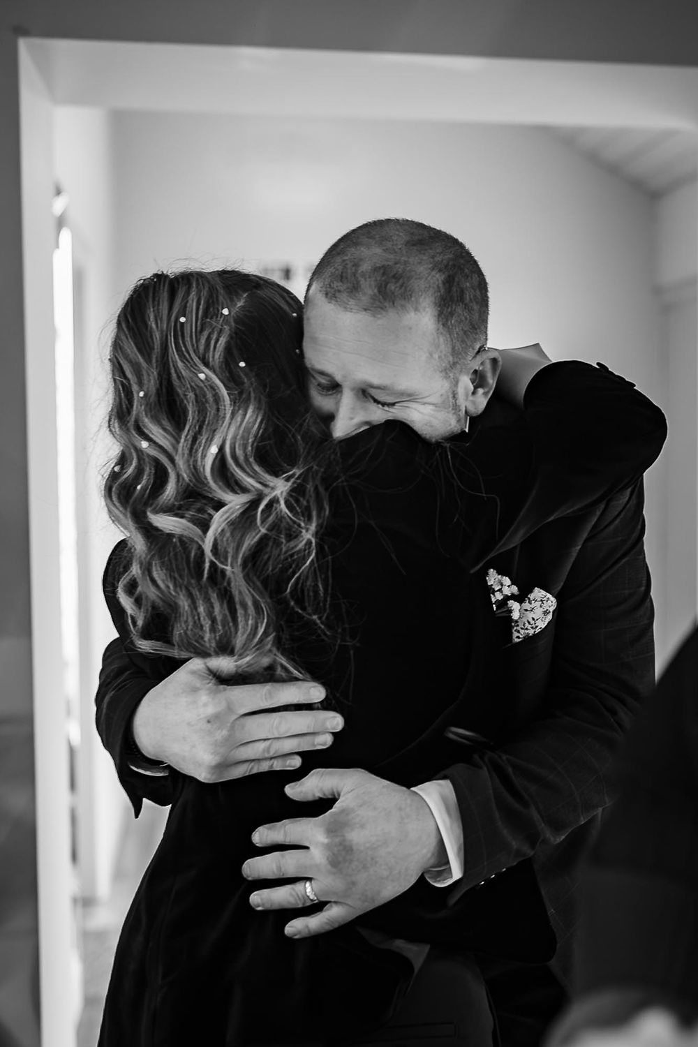 Black and white intimate moment captured of two people embracing in an emotional hug indoors.