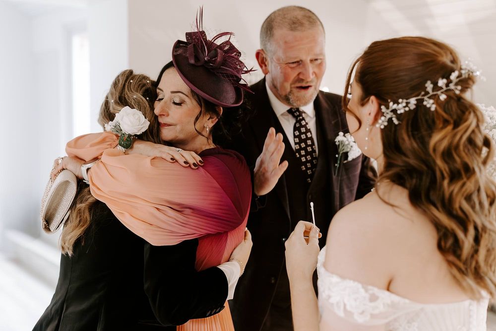 Emotional wedding scene showing warm embraces and reactions during a special moment indoors.