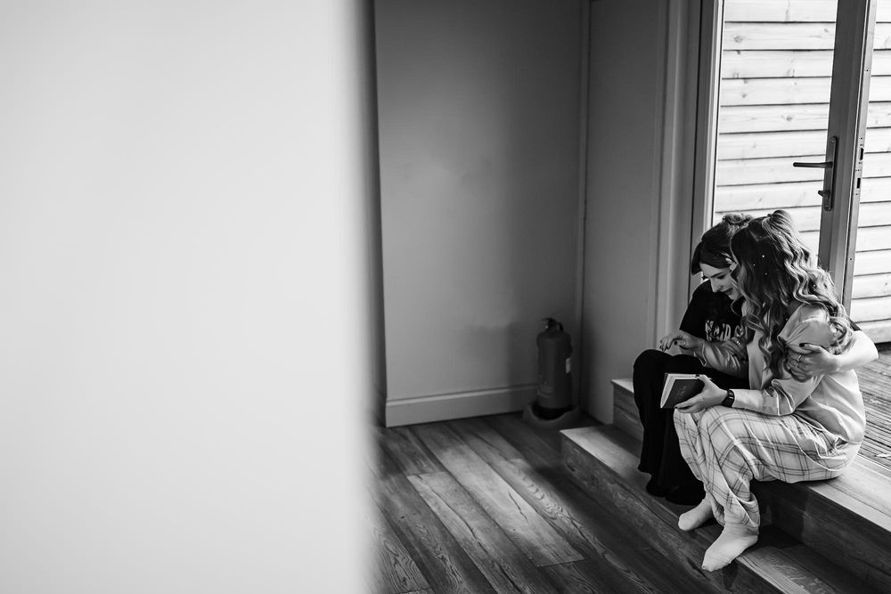 A person sits alone in a dark room by a window, creating a contemplative and moody atmosphere.