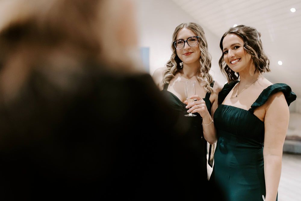 A group of friends in emerald green dresses pose together during a formal event.