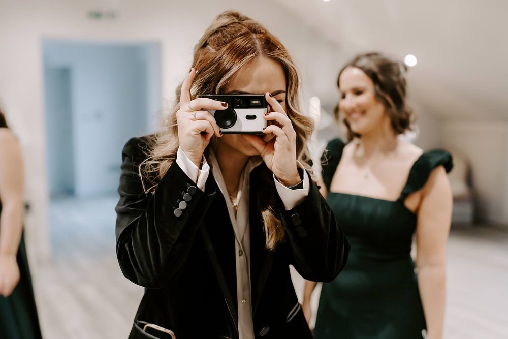 A photographer wearing black captures moments with a vintage camera at an elegant event.