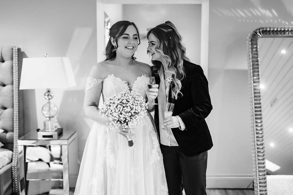 Black and white wedding photo showing emotional first look reactions in a bright indoor setting.