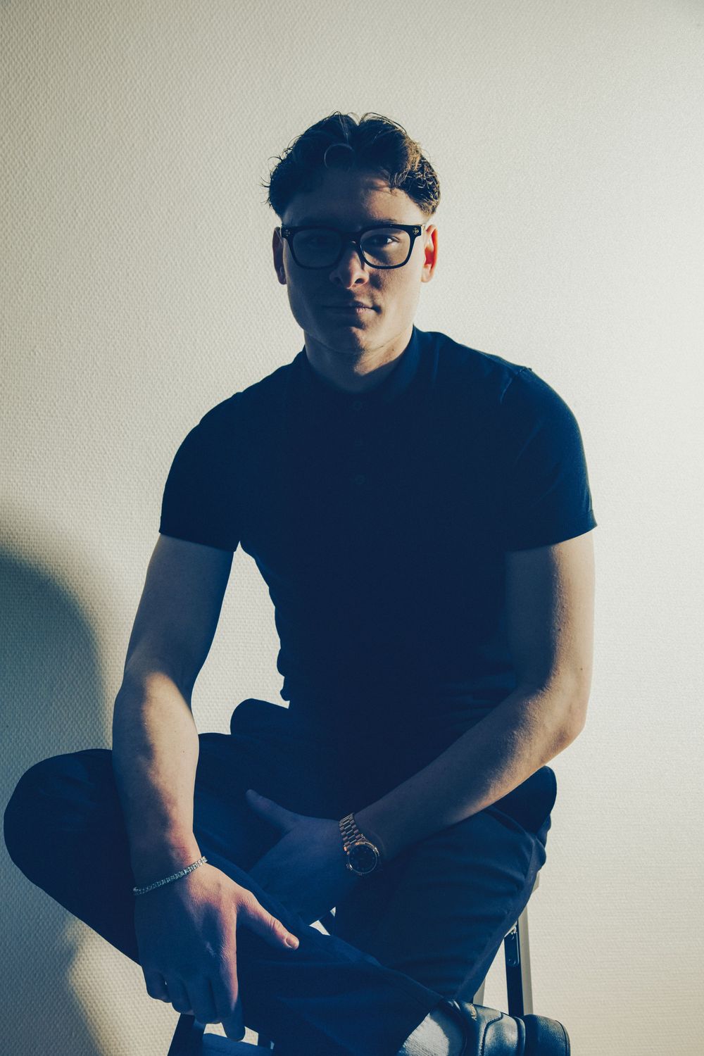 Artistic portrait series showing a person in black clothing sitting on a chair against a light background.