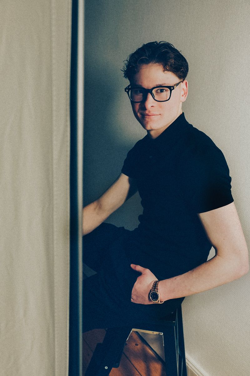 A series of four moody portrait photos showing someone in black attire against a light wall.