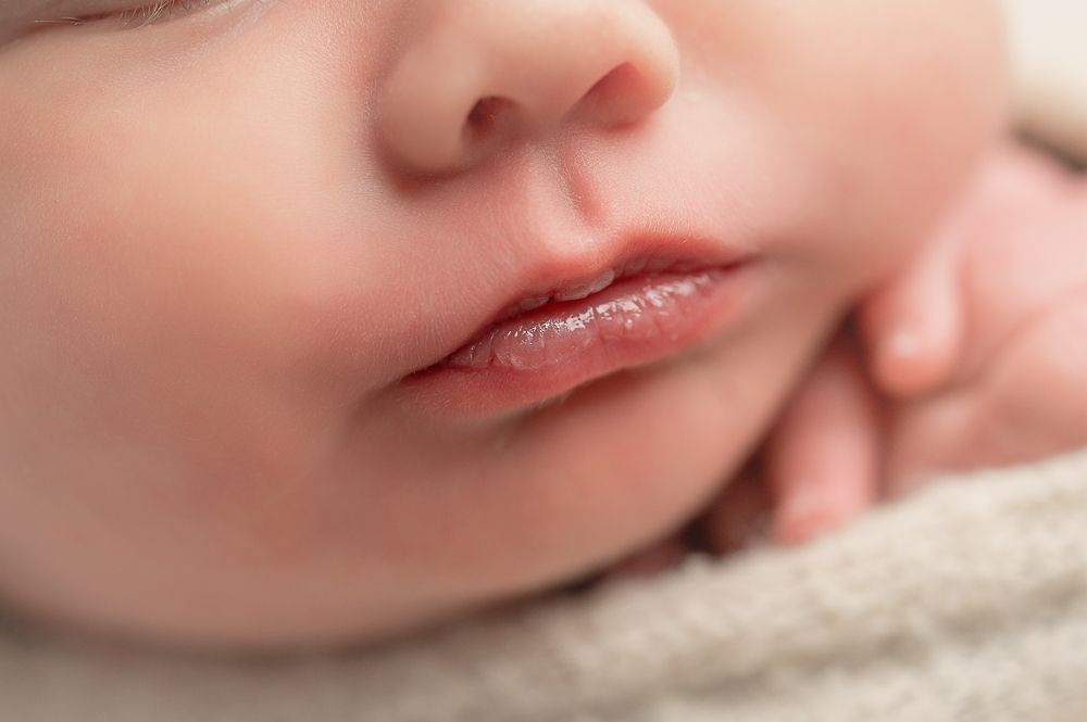 Close up macro photo of newborn lips and skin showing texture and detail in soft lighting.