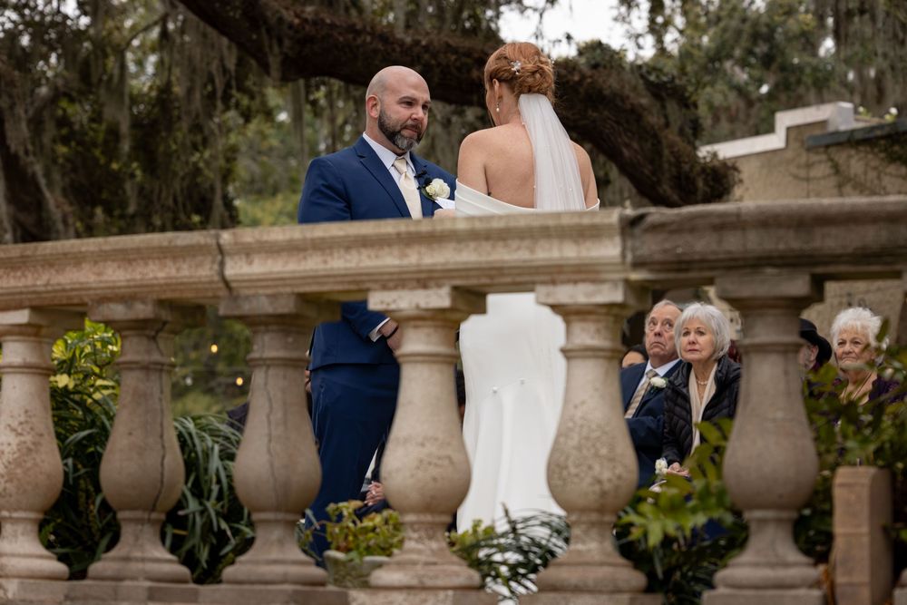 Wedding couple sharing a moment on an ornate stone balcony with Spanish moss in background.