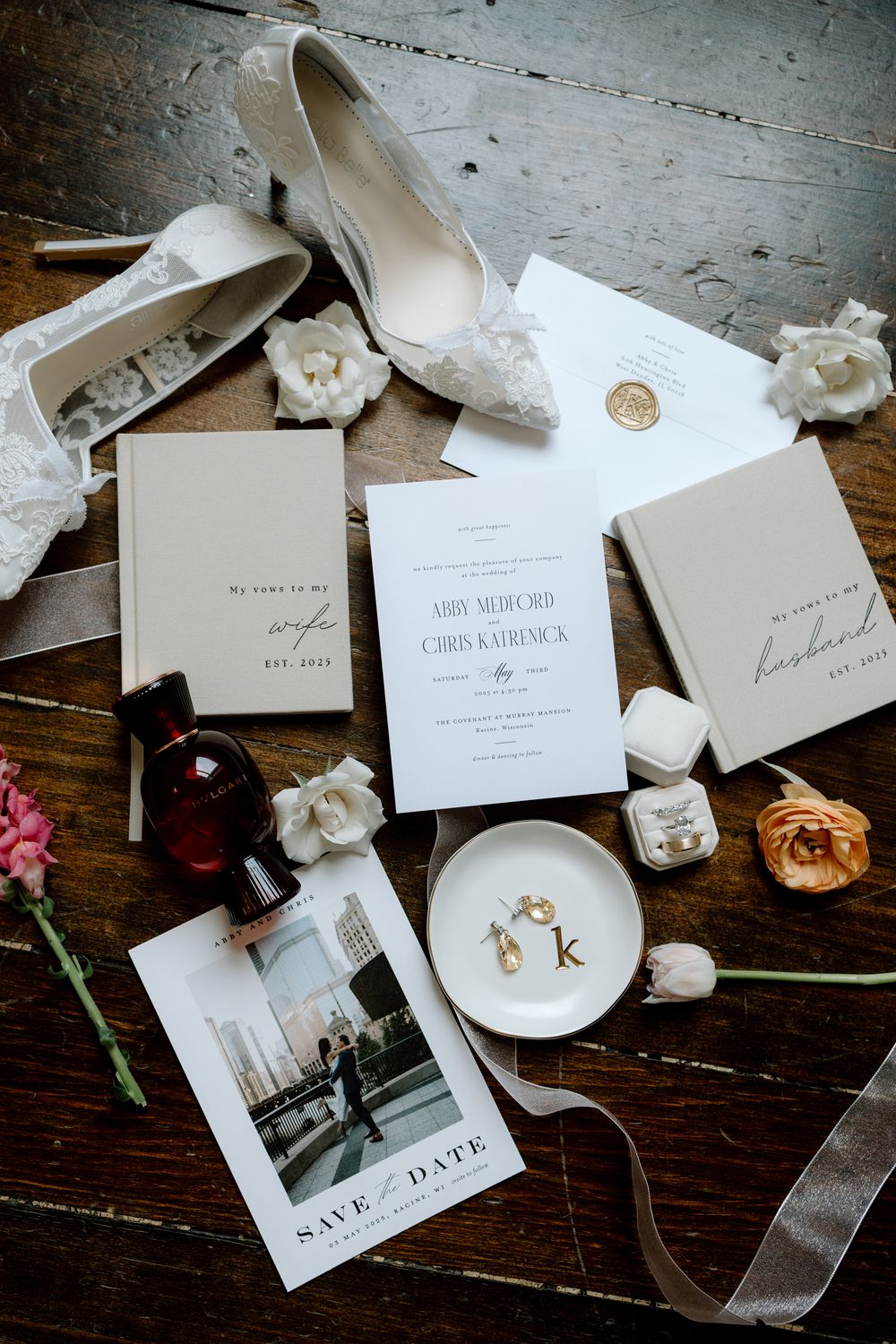 Wedding invitation suite with save the date cards, envelopes, and floral accents arranged on rustic wooden surface.