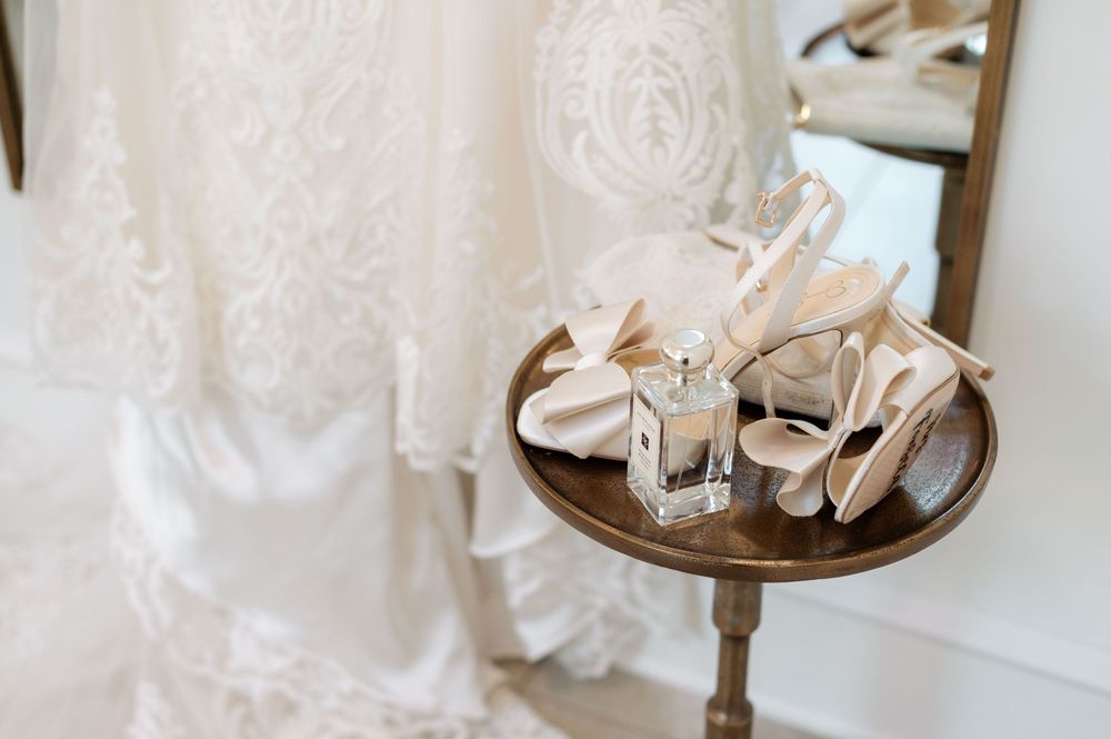 A collection of delicate vintage lace wedding dresses and bridal accessories displayed on mannequins and hangers.