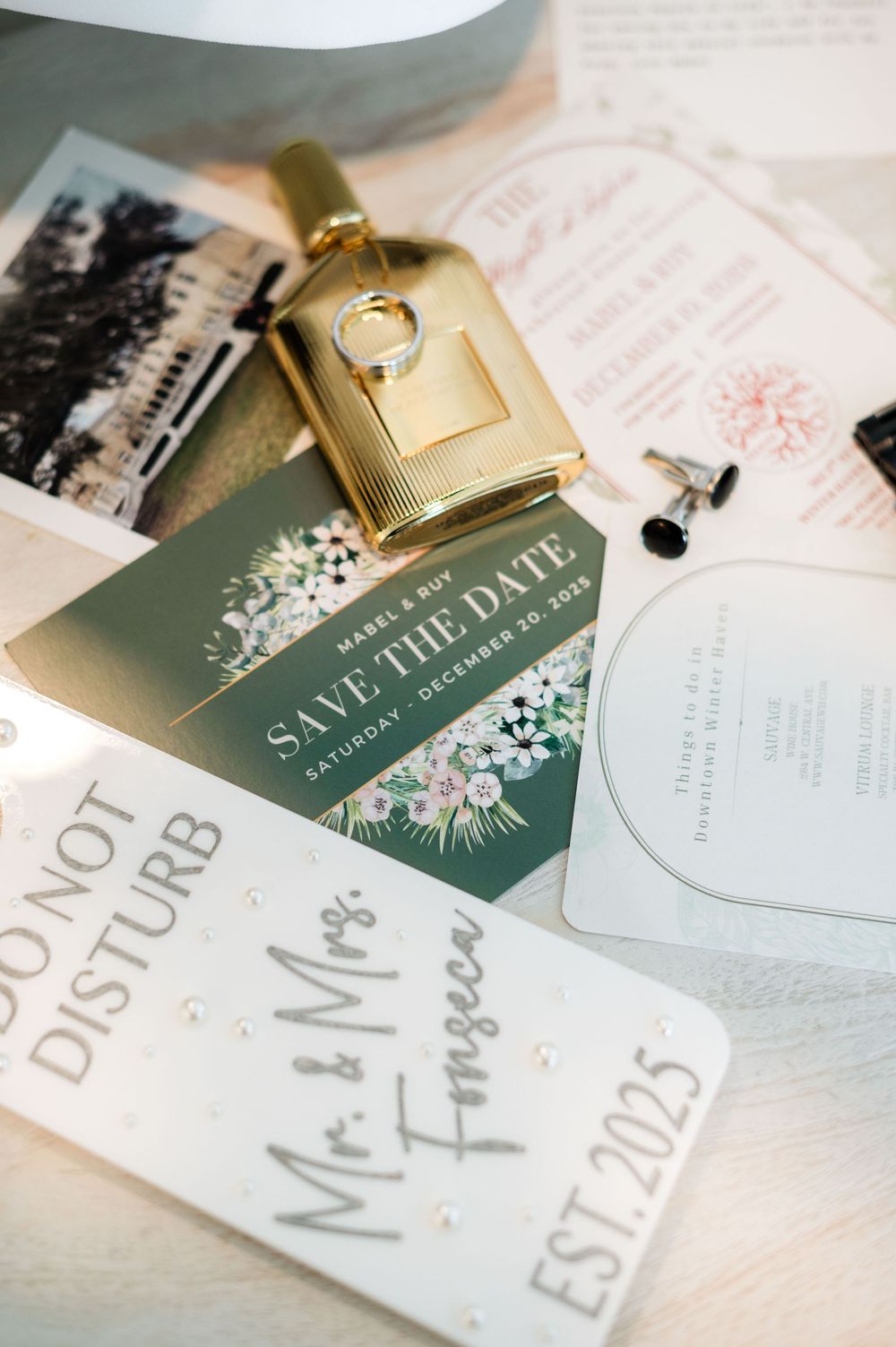 Wedding stationery including save the date cards and gold key detail arranged on white surface.