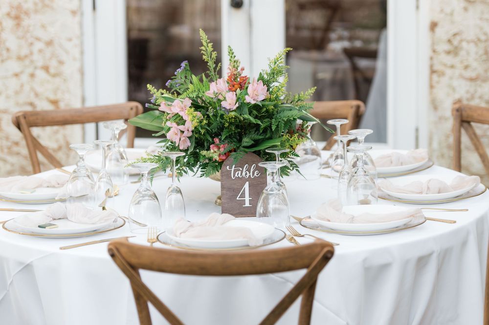 Elegant wedding reception table setting with white linens and floral centerpieces.