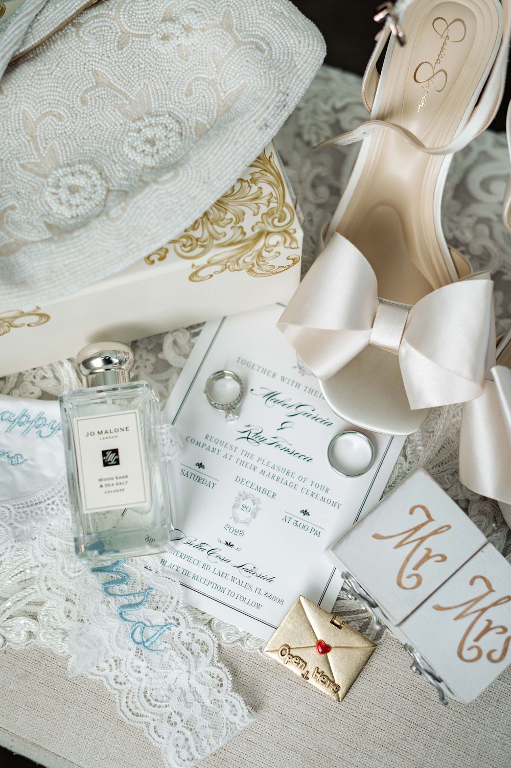 Elegant wedding details including lace, invitations, and delicate accessories arranged on a light background.