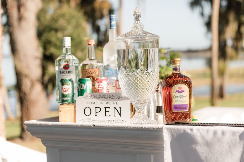 Elegant bar setup with crystal decanters and liquor bottles on display at an outdoor wedding reception.