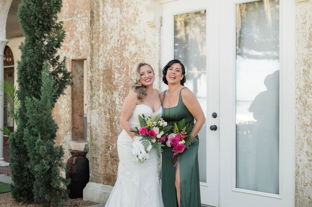Elegant white church doors with greenery and pink floral arrangements.