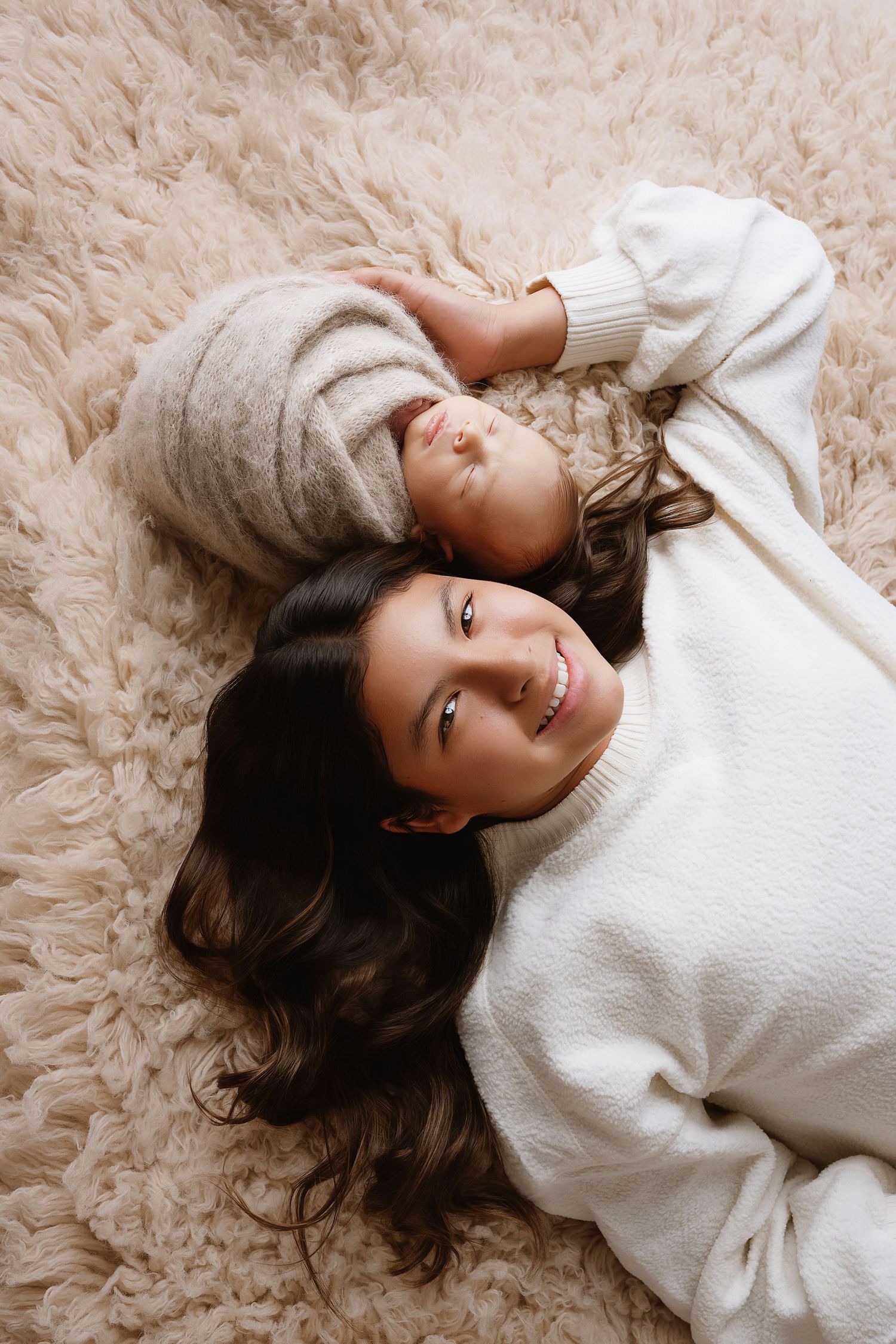A person in a white sweater lies on a plush beige carpet in a series of relaxed poses.