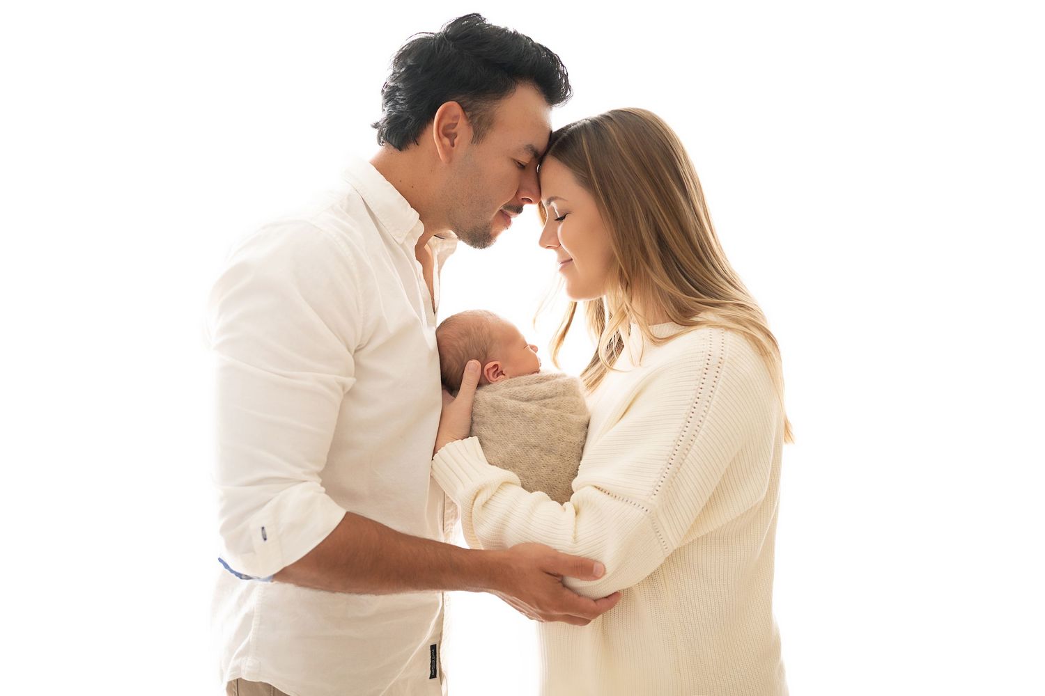 A romantic couple in white outfits shares intimate moments in a bright studio setting.