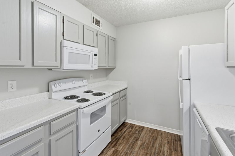 Modern white kitchen interior with stainless steel appliances and hardwood flooring.