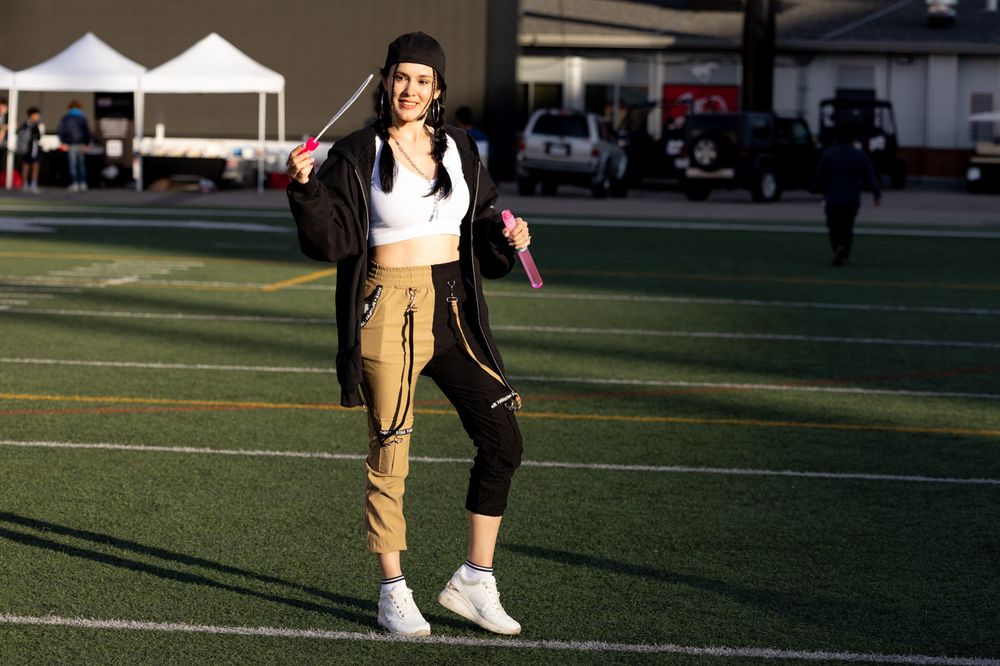 Athletes practicing on a football field at sunset with long shadows cast on the turf.