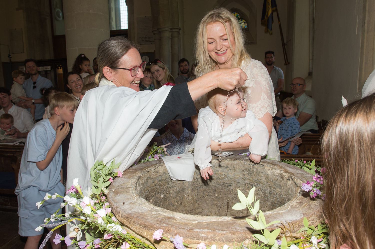 A woman vicar baptises baby with water during a christening ceremony at a church in Buckinghamshire, captured by Abigail's Studio.