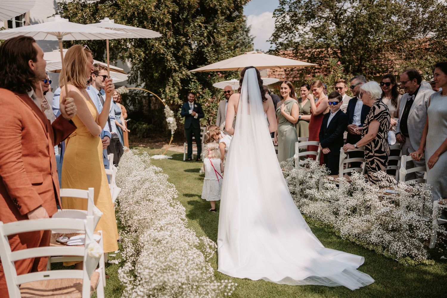 A beautiful outdoor wedding ceremony setup with white chairs and floral arrangements lining the aisle.