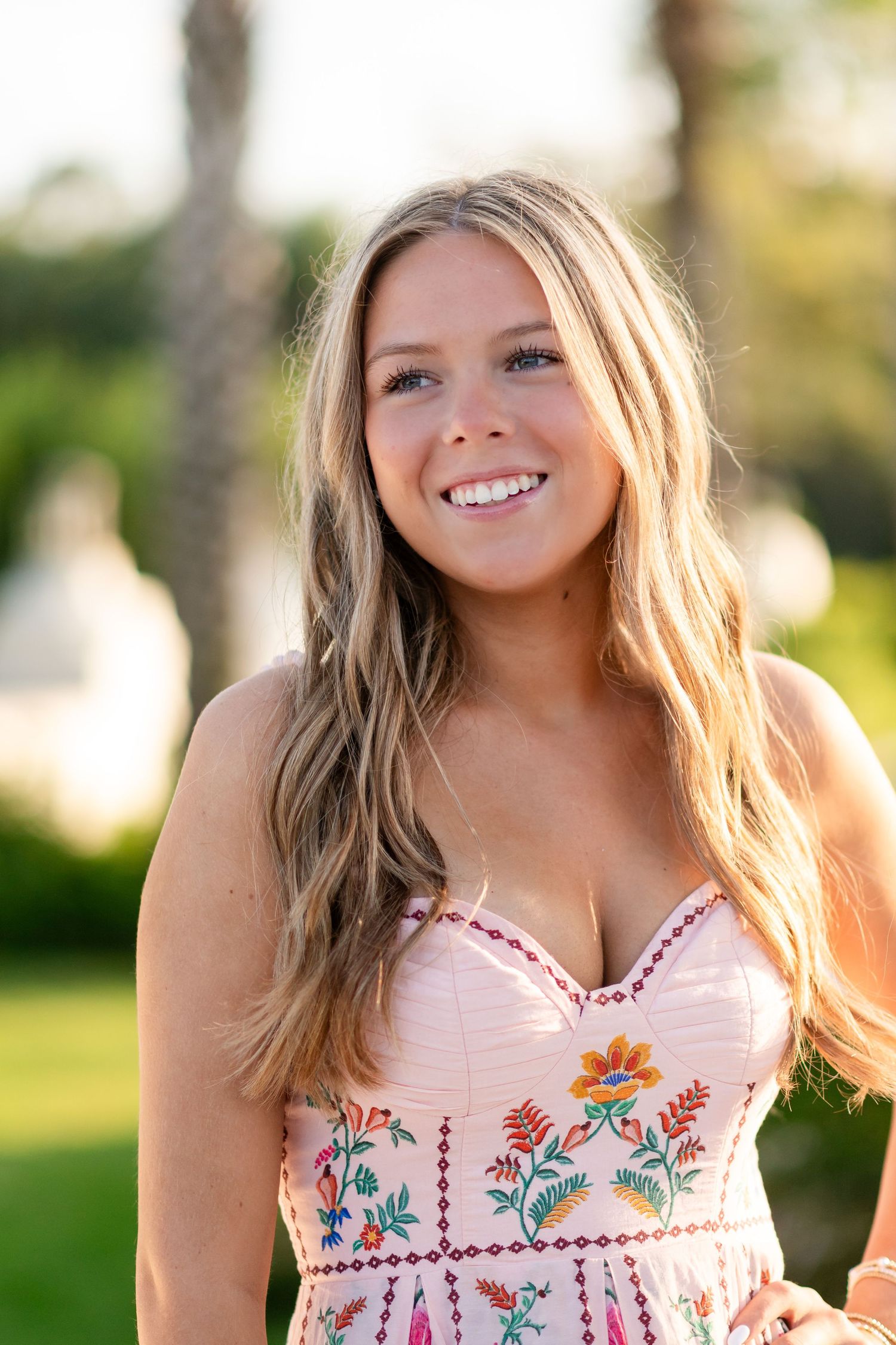 A series of photos showing embroidered floral details on a white summer dress in an outdoor garden setting.