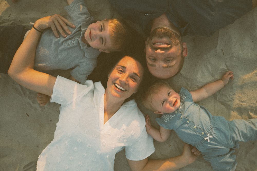 A group of people laughing and having fun while laying down together in a playful moment. Family Photographer Carolina Beach, NC