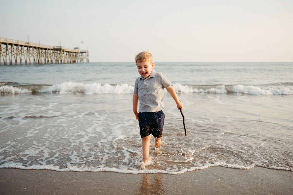 A childplaying in the surf at sunset. Natural Light Family Photographer, Wrightsville, NC Photographer