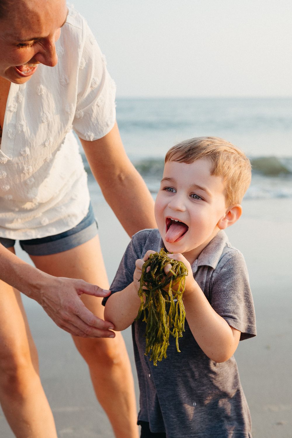 Sequence of child playing with seaweed on sunny beach while adult watches nearby. Wilmington NC Family Photographer