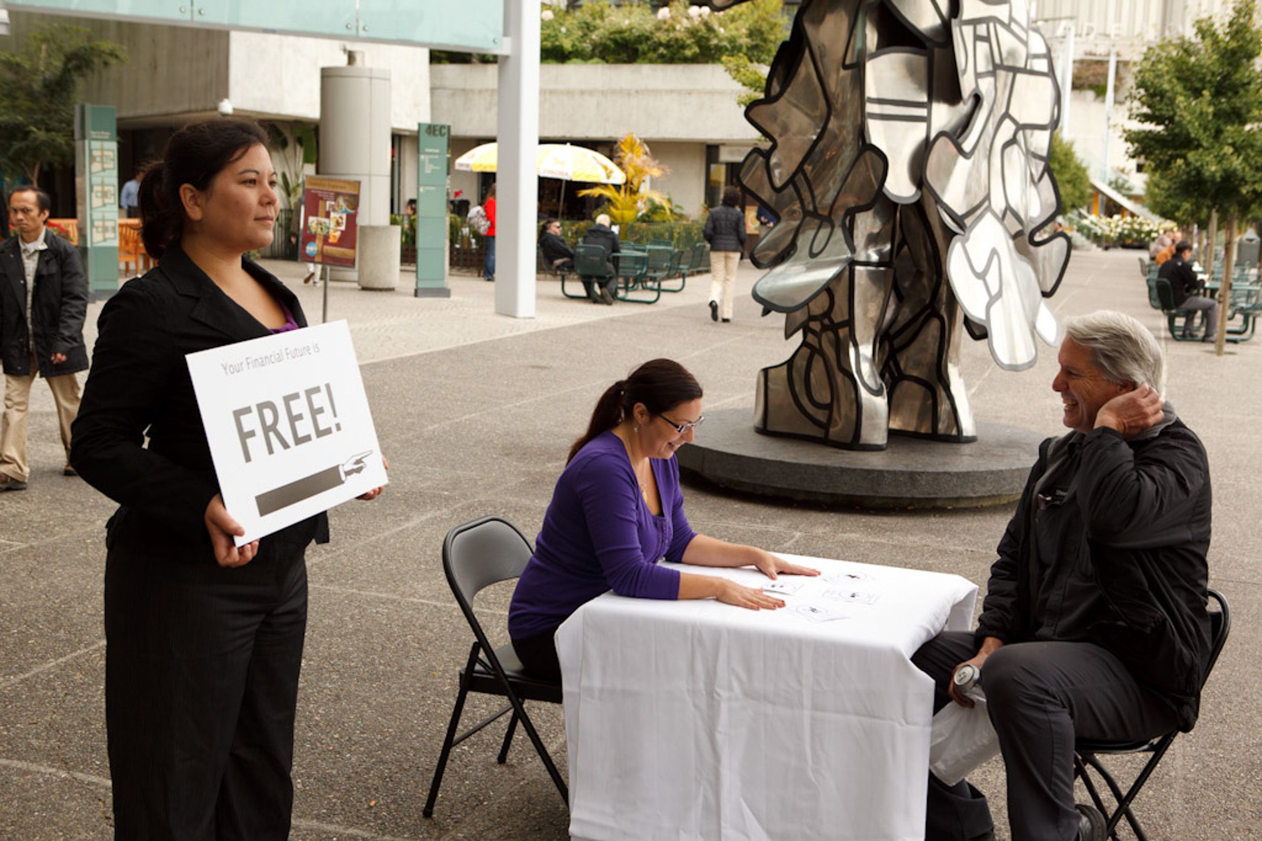 People gathered around tables with white tablecloths at an outdoor event space.