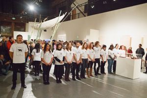 Panoramic view of people lined up against gallery walls for a performance piece.