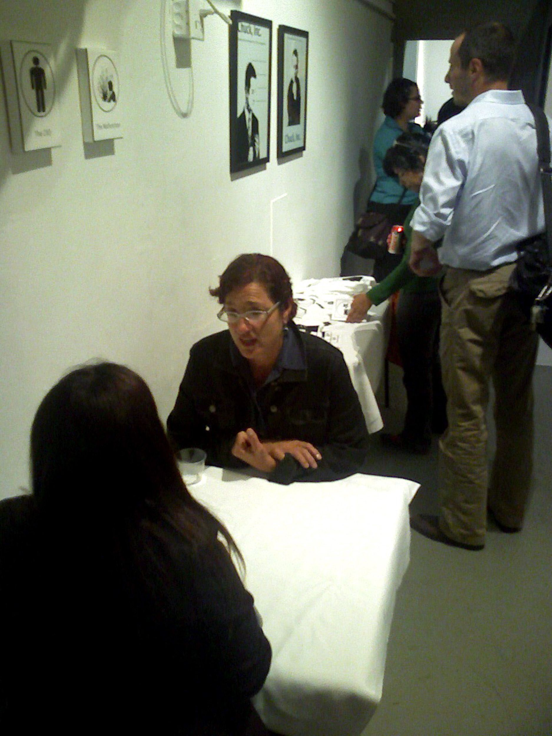 People viewing artwork displayed on walls in a gallery setting.