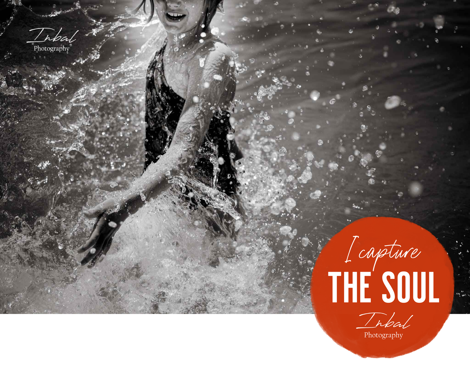 A black-and-white photo of a girl splashing water with her hand in the sea, capturing the playful motion and energy in the moment.