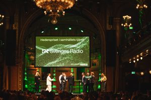 Elegant ballroom with chandeliers and green lighting features multiple screens displaying presentation content.