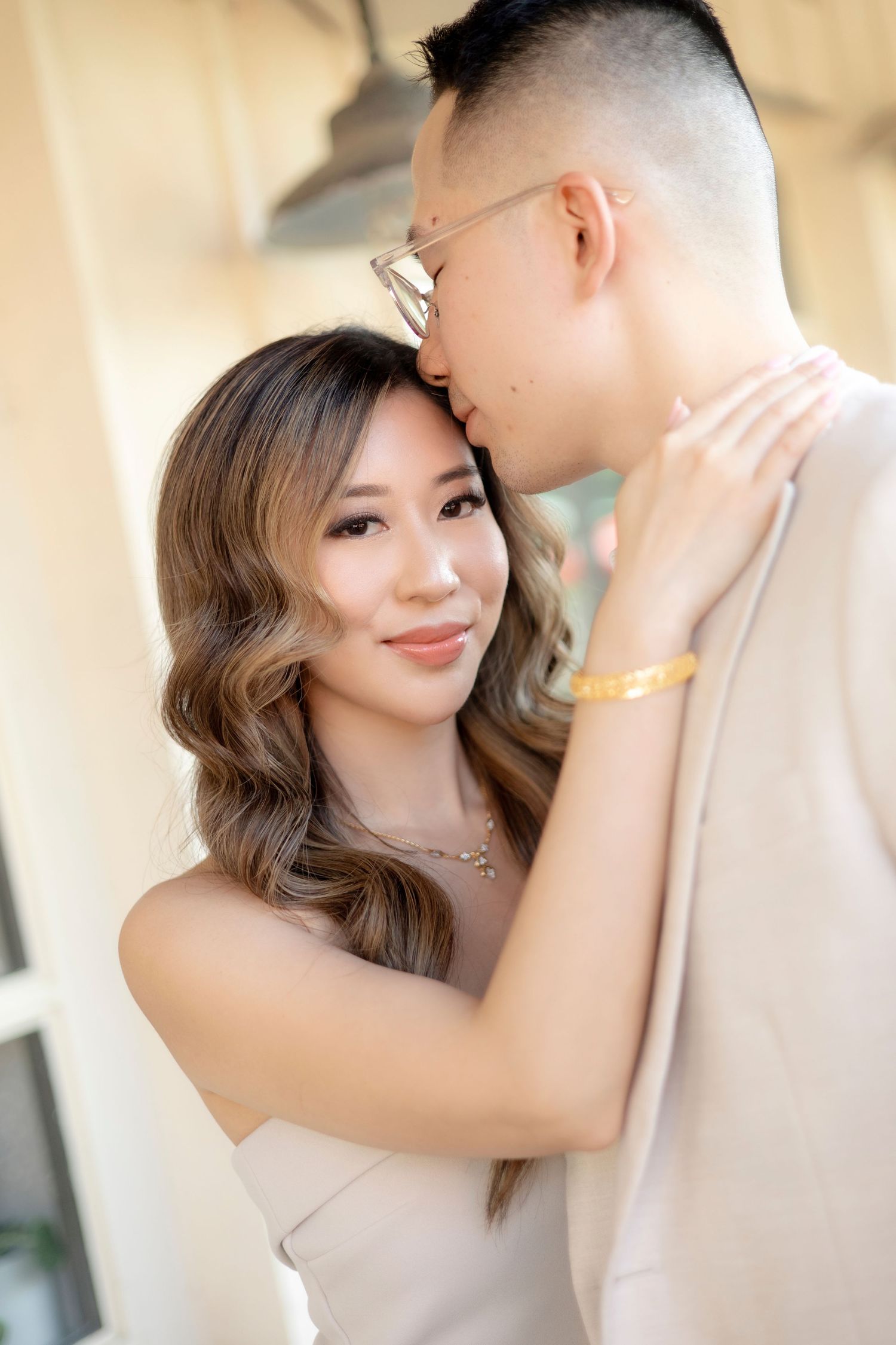 Wedding couple walks down the aisle at an indoor ceremony decorated with white chairs and dandelion-like light fixtures.