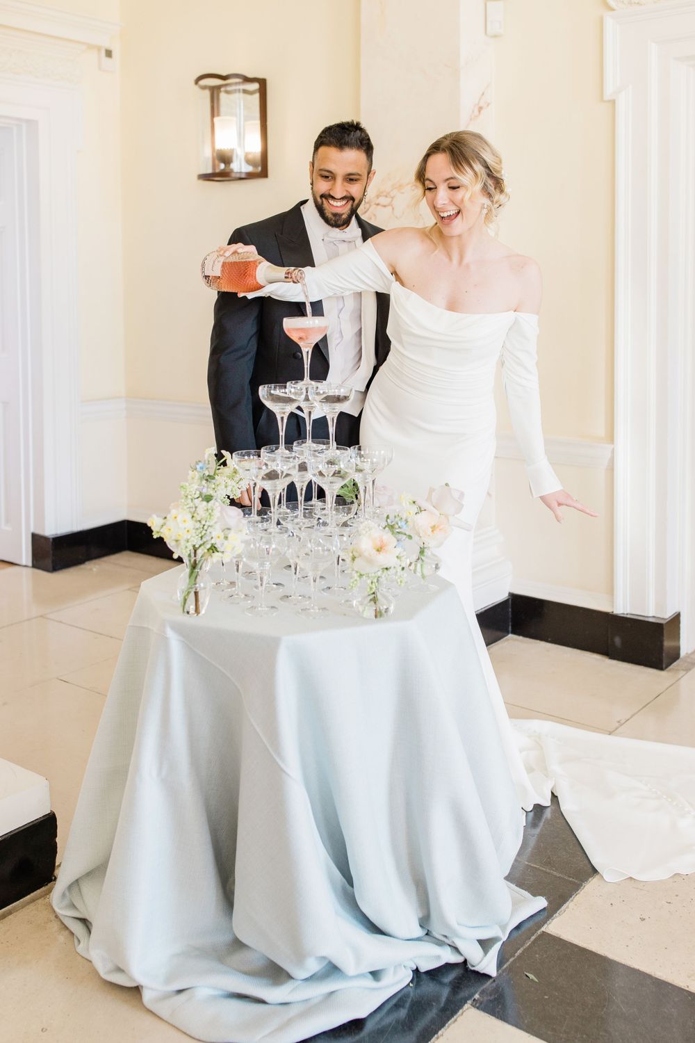 Couple pouring champagne into tower of glasses at elegant wedding reception at Botleys Mansion, by Maddie Waters Hampshire Photographer
