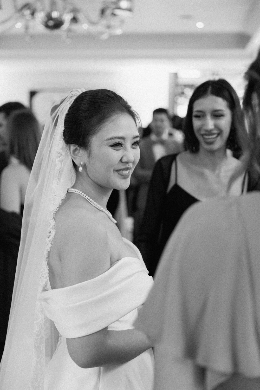 Black and white candid wedding reception moment with elegant off-shoulder bridal gown at Corinthia London by Maddie Waters Photography