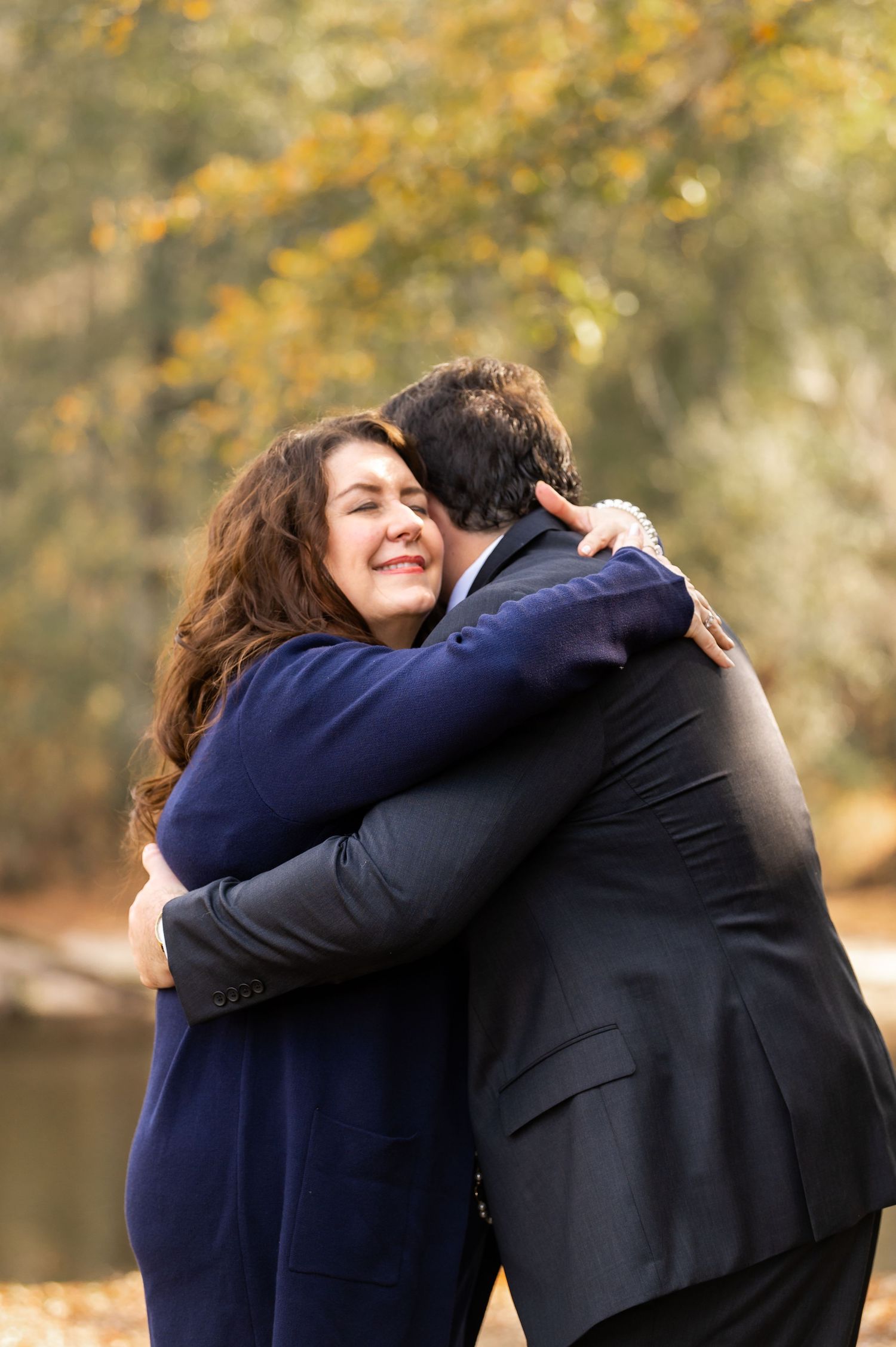 Intimate embrace between wedding attendees outdoors during autumn.